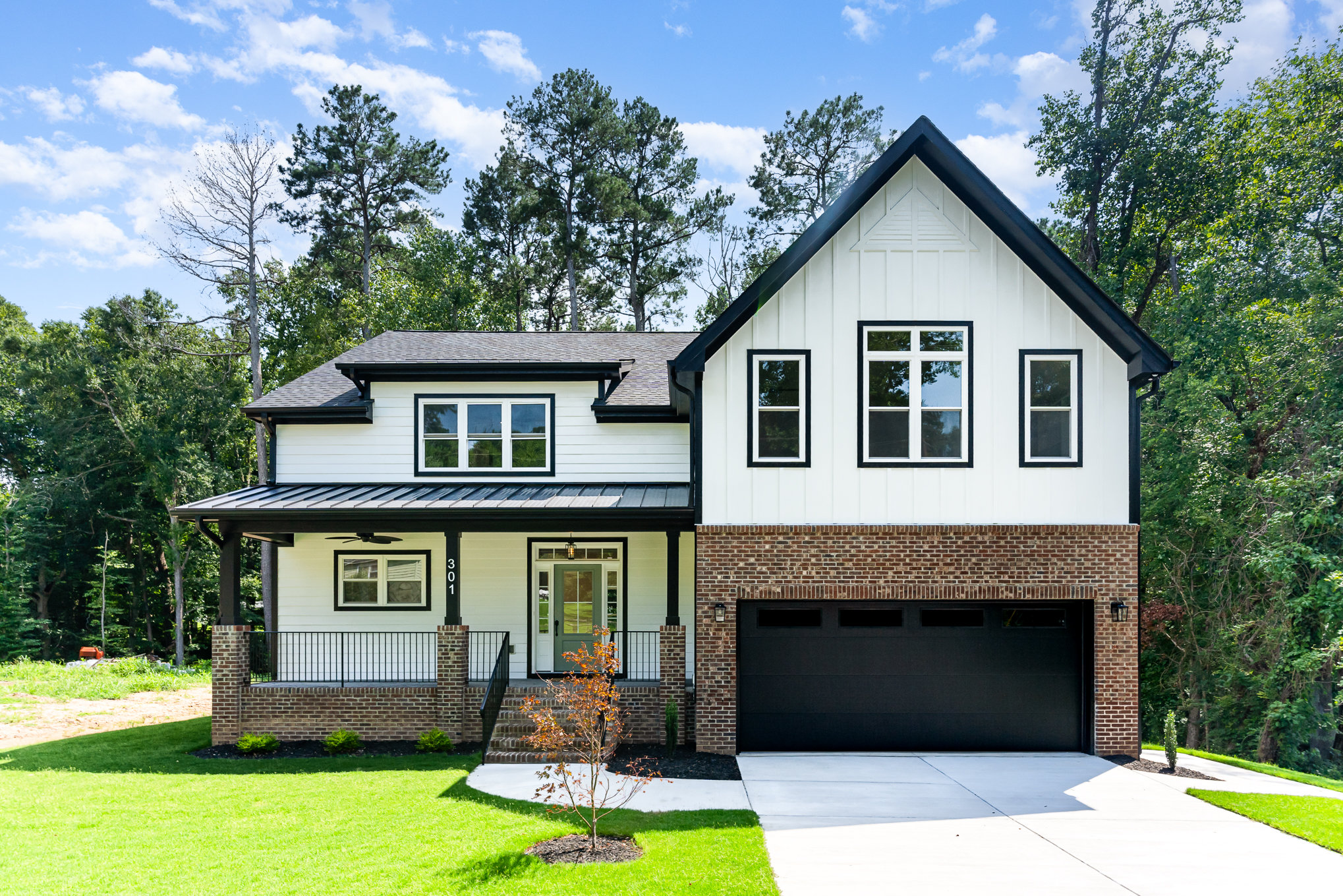 Finished custom home exterior with black garage and white siding